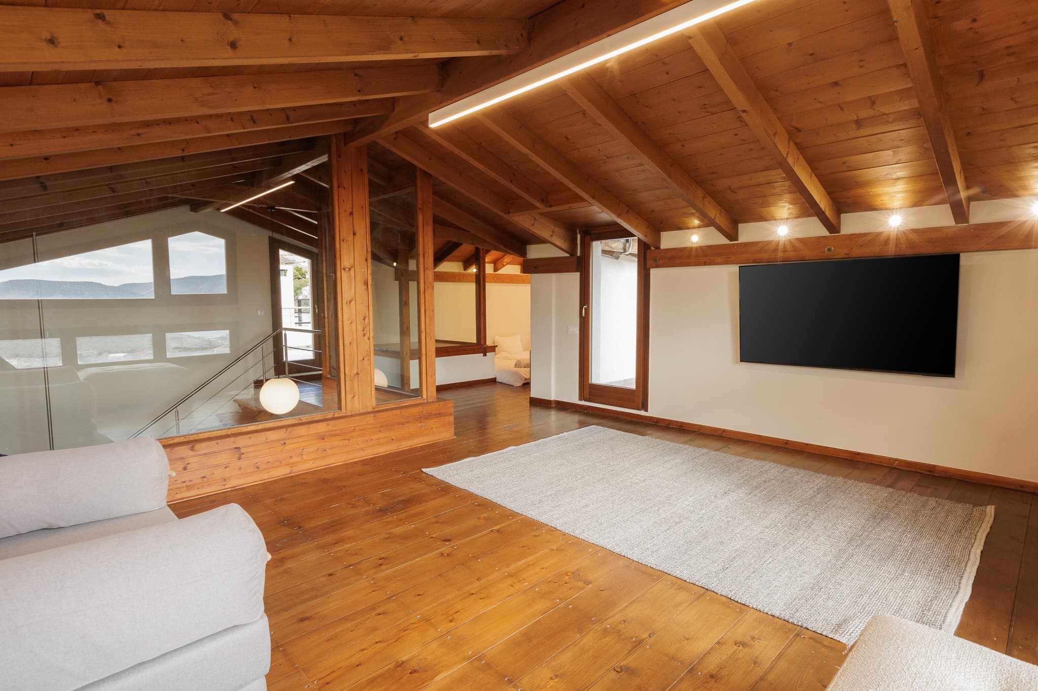 Attic-level workshop space at Villa Lithos with wooden beams and a large screen