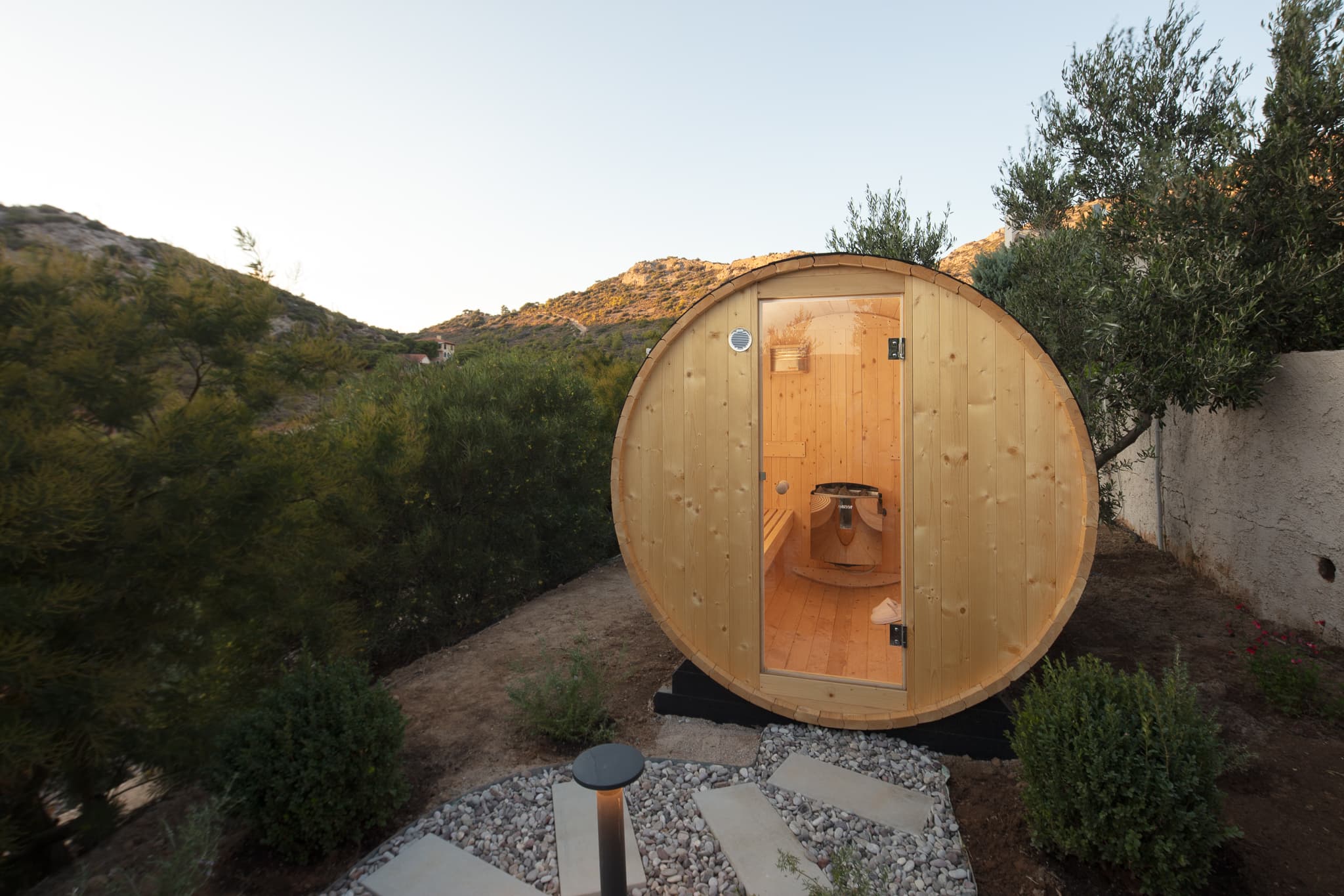 Outdoor barrel sauna among olive trees